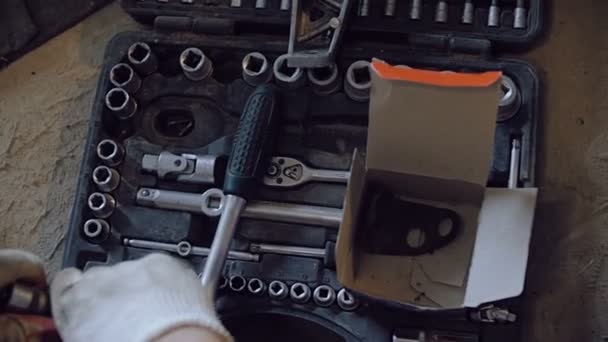 Les mains dans les gants de travail retirent la buse de la clé et la mettent dans la boîte à outils .