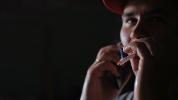 Un hombre con una gorra roja fuma un cigarrillo . — Vídeo de stock