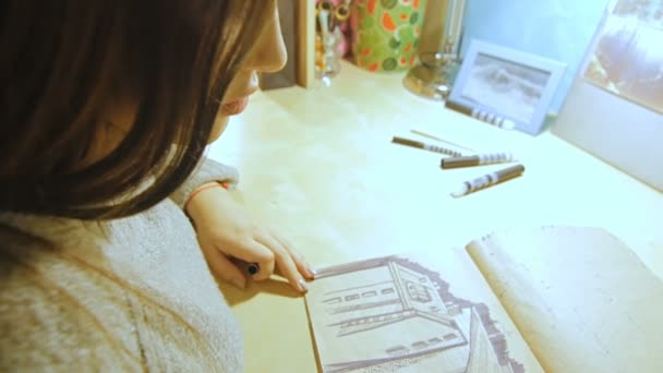 A young woman opens the marker and starts drawing in the album. — Stock Video