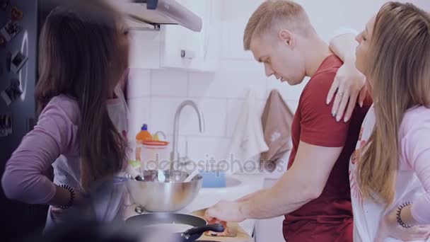 Una giovane coppia sta cucinando frittelle con il pesce in cucina . — Video Stock