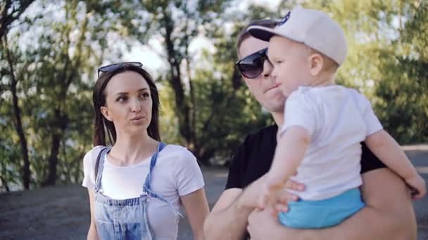 Een echtpaar met een kind loopt langs de kade. — Stockvideo