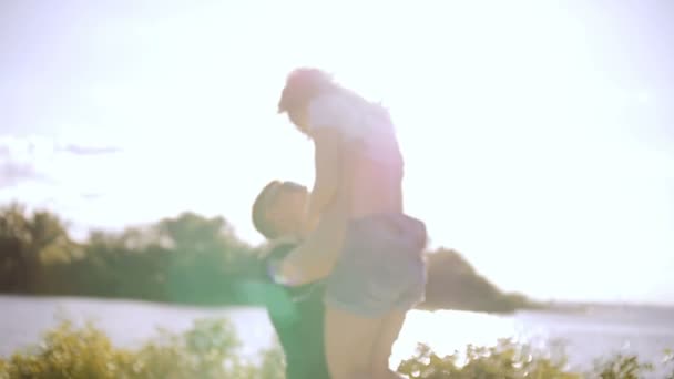 Un giovane uomo solleva una giovane donna tra le sue braccia . — Video Stock