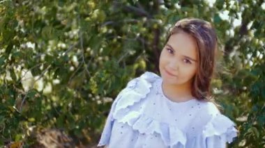 Ağaçlar yeşil yeşillik bir arka plan üzerinde kamera önünde kız dansları.