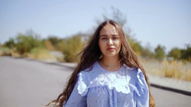 Bir ışık içinde genç bir kadın yolda duran ve kameraya bakıyor.