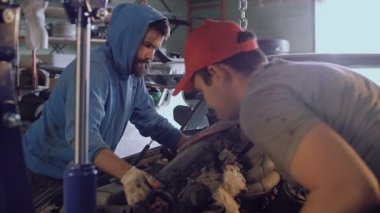 İki otomatik mekanik arabanın kaputu küçük bir vinç yardımıyla motor ayıklamak.