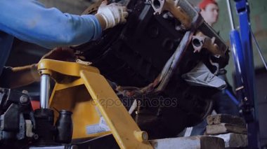 Bir vinç yardımıyla iki mekaniği üzerine bir sepeti, bir otomobil motoru daha fazla ulaşım için yük.