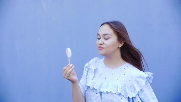 Mladá krásná žena s dlouhými vlasy olizuje zmrzlina. — Stock video