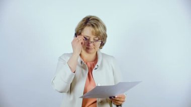 Beyaz ceketli orta yaşlı bir kadın o onun elinde tutan belge görmek için gözlük Giydir.