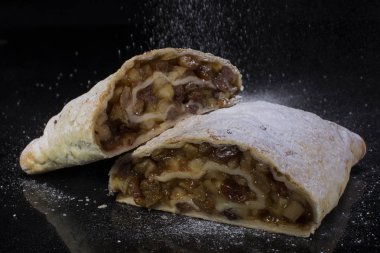 Apple strudel yakın çekim üzerinde siyah bir arka plan kesme pudra şekeri serpilir