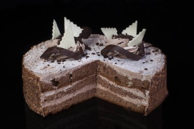 Beyaz pastasından çikolatayla döktü ve yağı bir siyah arka plan üzerine krem ile dekore edilmiş