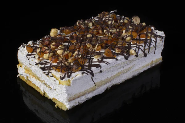 一块蛋糕特写 上面洒满了坚果葡萄干和巧克力的白色奶油 — 图库照片