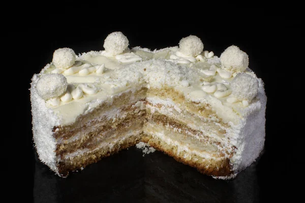 在黑色背景上切下一块白色的蛋糕 上面有椰子剃须 — 图库照片