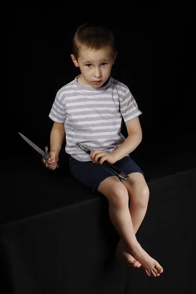 Little boy with a dagger on a black background