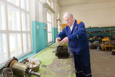 Belarus, Gomil şehri, 25 Nisan 2019. Ahşap işleme tesisi. Elektrikçi eski bir elektrikli motoru tamir ediyor