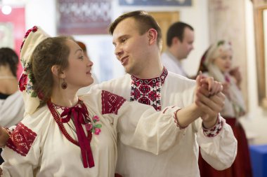 26 Kasım 2016 'da Belarus, Gomiel şehri. Ulusal elbiseli bir çift halk danslarında dans ediyor. Nakışlı gömlekli bir adam ve bir kadın dans ediyorlar.