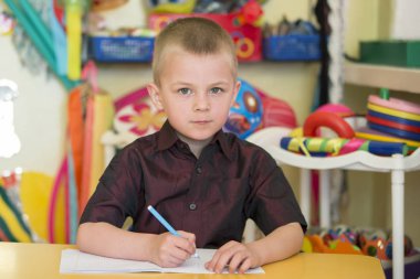 Belarus, Gomel şehri, 26 Nisan 2019. Anaokulunda açılış günü. Çocuk bir anaokulu öğrencisi. Altı yaşında bir çocuğun portresi. Not defteri ve kalemi olan ilkokul öğrencisi..