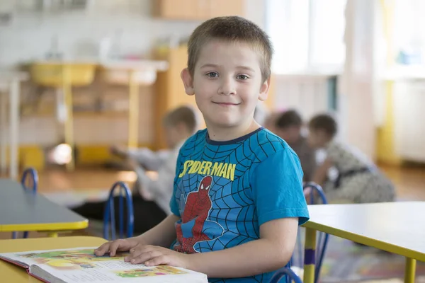 ベラルーシ ゴメル市 2019年4月26日 幼稚園でのオープン日 その少年は未就学児です 本を持つ6歳の子供の肖像画 机の上の中学生 — ストック写真