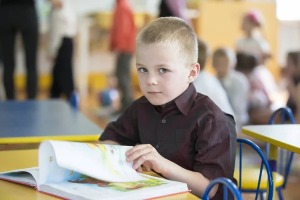 ベラルーシ ゴメル市 2019年4月26日 幼稚園でのオープン日 その少年は未就学児です 本を持つ6歳の子供の肖像画 机の上の中学生 — ストック写真