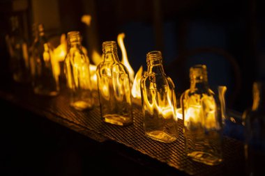 Cam fabrikası. Cam endüstrisi. Cam şişe konveyörde yanıyor.