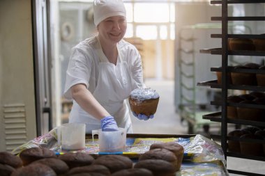 Belarus, Gomil şehri, 25 Nisan 2019. Fırın. Ekmek dükkanında endüstriyel Paskalya pastası üretimi. İşçi aşçısı Paskalya pastasını süslüyor.