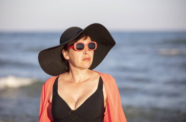 Portrait of an old woman in a hat on a background of the sea