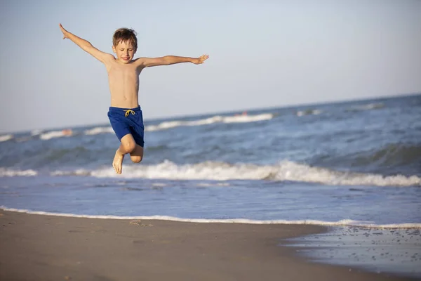 Uma Criança Brinca Praia Rapaz Feliz Salta Alto Junto Mar — Fotografia de Stock