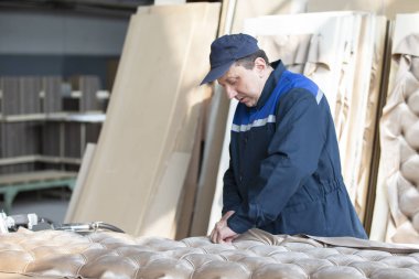 Belarus, Gomil şehri 29 Nisan 2019. Ahşap işleme tesisi. Yatak üretimi için atölyede çalışan bir işçi. Efendi lüks mobilyalar yapıyor. Araba perdelendi. Ahşap işleme endüstrisi