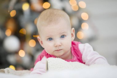 Yeni yıl ağacının arka planında neşeli bir bebeğin portresi. Yeni doğmuş kız Noel 'de