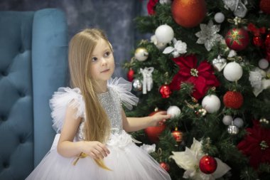 Güzel bir çocuk Noel ağacını süslüyor. Noel zamanı zarif bir kız..