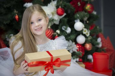 Noel hediyesi olan güzel bir çocuk. Yeni yıl ağacında giyinmiş bir kız..