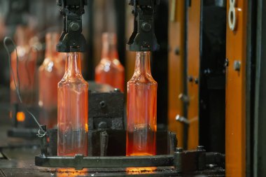Cam fabrikası. Cam endüstrisi. Cam şişeler yapma süreci. Taşıyıcı bantta erimiş cam kaplar.