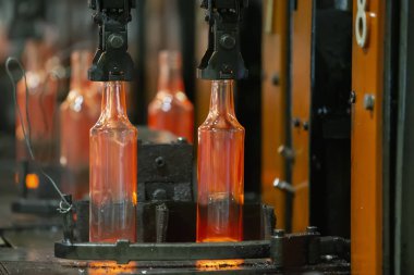 Glassworks. Glass industry. The process of making glass bottles.Molten hot glass containers on conveyor belt clipart