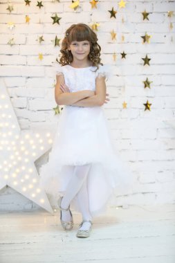 Beyaz elbiseli, dikey olarak zarif bir çocuk. Yedi yaşında bir manken.