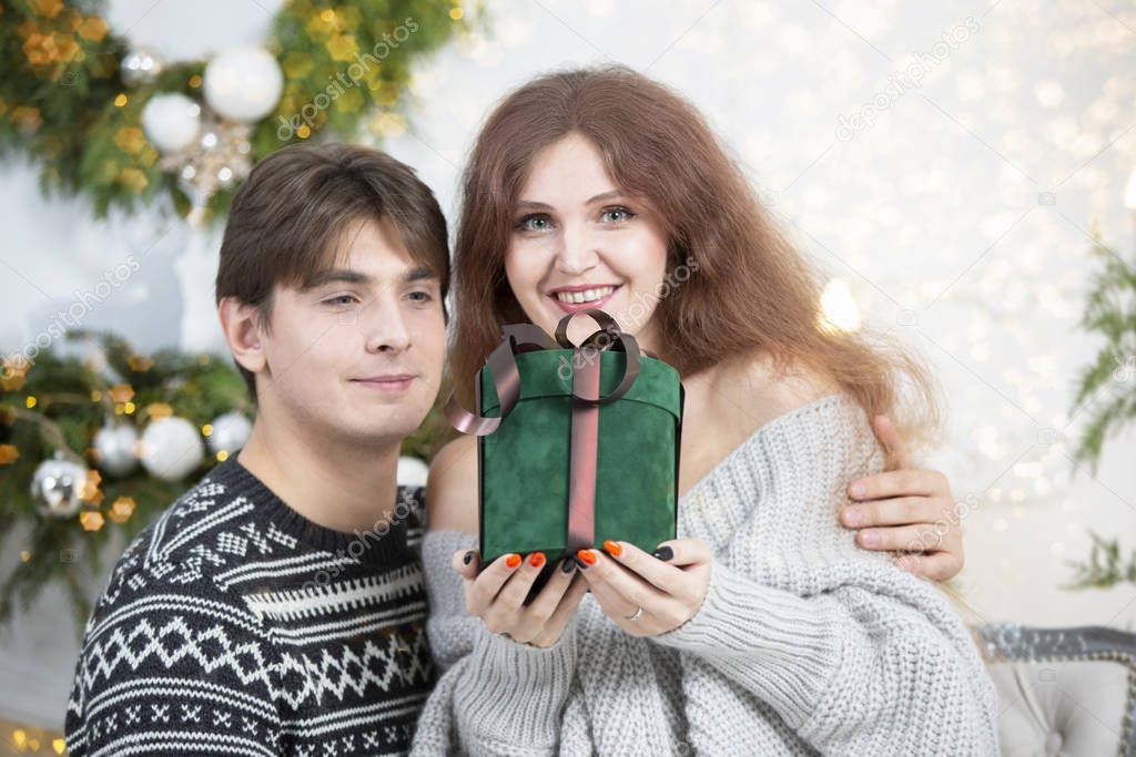 A man gives a woman a Christmas present. Husband and wife in the New Year holidays. Get a surprise in the winter holidays. Christmas holidays concept.