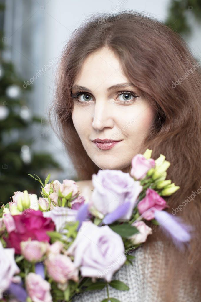 Vertical portrait of a beautiful long-haired woman with a bouquet of flowers