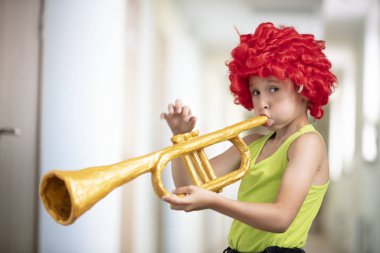 Parlak peruklu bir çocuk trompet çalar. Oyuncak müzik aleti olan komik çocuk. Geleceğin sanatçısı