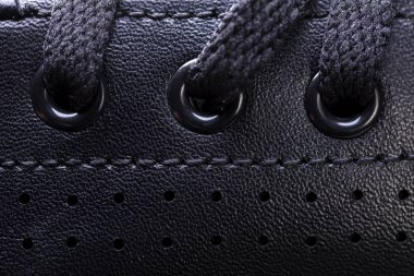 Bağcıklı siyah bir botun parçası. Koyu renk bir ayakkabı parçası. Bir parça spor ayakkabı..