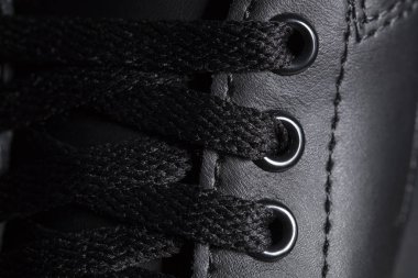 Bağcıklı siyah bir botun parçası. Koyu renk bir ayakkabı parçası. Bir parça spor ayakkabı..