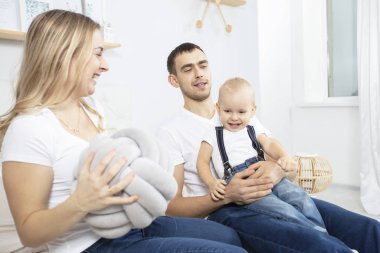 Anne, baba ve küçük oğlu evde oynuyorlar. Çocuklu genç bir aile.