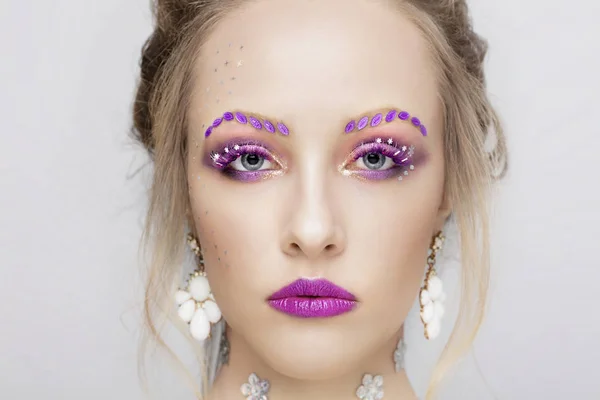 一个年轻女孩的脸有紫色妆容的模特奇形怪状的眼睛 — 图库照片
