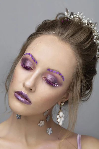 Model girl with bright makeup with eyes closed. Fashion makeup. Woman with violet restresses and eyebrows.