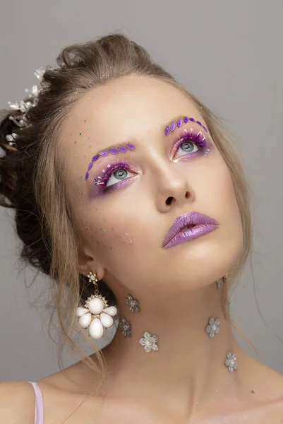 Model girl with bright makeup. Fashion makeup. Woman with violet restresses and eyebrows. Beautiful young face.
