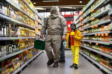 Beyaz Rusya, Minsk, 13 Nisan 2020. Coronavirus koruması. Gaz maskeli bir çocuk ve dükkanda kimyasal koruma kıyafeti giyen bir adam. İnsanlar COVID 19.Coronavirüs ve panik satın alma konsepti satın alıyor.