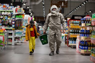 Beyaz Rusya, Minsk, 13 Nisan 2020. Coronavirus koruması. Gaz maskeli bir çocuk ve dükkanda kimyasal koruma kıyafeti giyen bir adam. İnsanlar COVID 19.Coronavirüs ve panik satın alma konsepti satın alıyor.