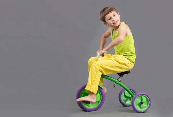 Παιδί Ένα Τρίκυκλο Γκρι Φόντο Αστείο Αγοράκι Παίζει Αγόρι Κάνει — Φωτογραφία Αρχείου