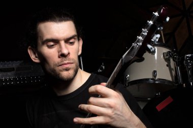 Bir adam gitar çalar. Karanlık bir arka planda müzik aleti olan bir adamın yüzü..