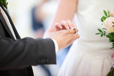 Düğün günü. Gelin yüzüğü damada giydirir. Yeni evlilerin elleri..