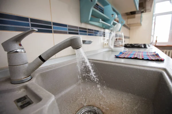 In the kitchen, water flows from a faucet into the sink.