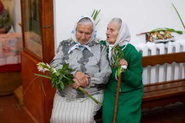 Belarus, Gomil şehri, 1 Nisan 2018. Şehir kilisesi. Palm Sunday. Rus büyükanneler. İki yaşlı kadın kilisede bir bankta.