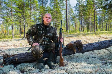 Avcı yakın tüfek ve wildfowls ile oturuyor. Çalıhorozu avcılık.